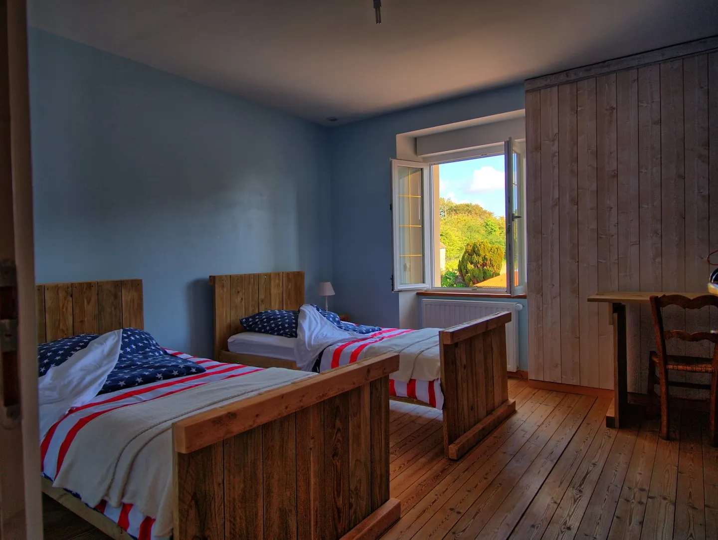 La chambre aux deux lits simples, murs bleu ciel et parquet