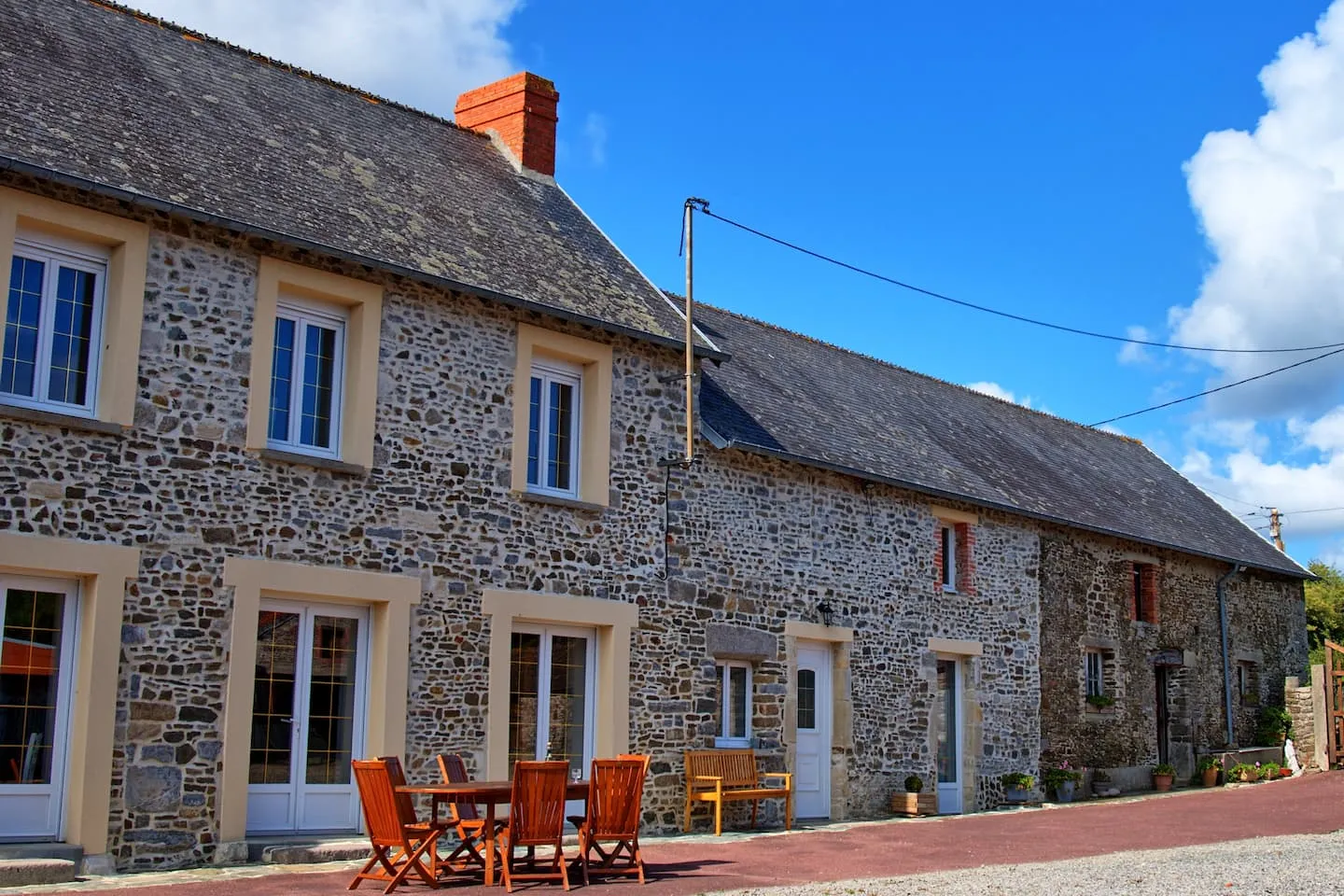 La longère en pierre et la table de la terrasse, dans la cour